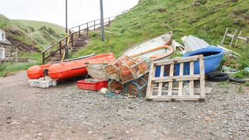 A gravel path leading to a staircase with boats and fishing gear piled up.
