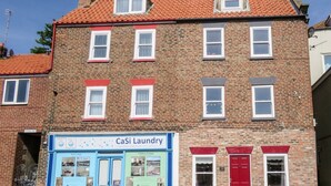 A brick building with multiple windows and a blue storefront labeled "CaSi Laundry." - Odd Sock Cottage (Whitby)