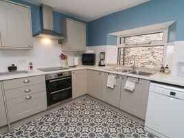 A modern kitchen with a built-in oven, a dishwasher, and a window with a stone wall view.