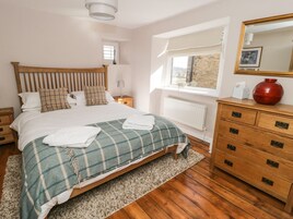 A neatly arranged bedroom with a wooden bed, a dresser, and a window with a view.