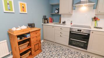 A compact kitchen with a microwave, oven, and a wooden cabinet with baskets.