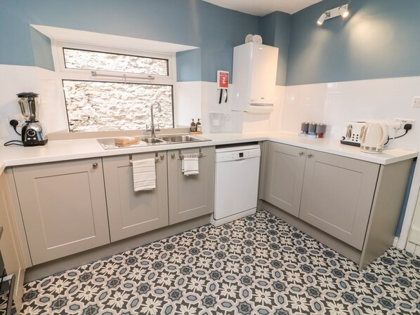 A modern kitchen with a dishwasher, sink, and a window above the countertop.