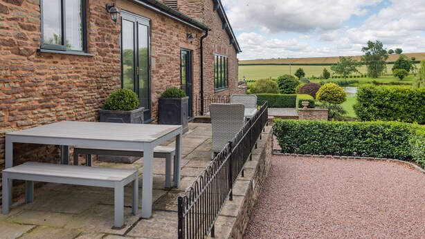 A stone building with a patio area, outdoor seating, and a view of the countryside. - Teal Barn Annexe (Hereford)