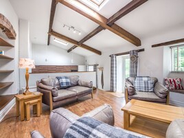 A spacious living area with wooden beams, a sofa set, a wooden coffee table, and a lamp.
