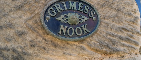 A stone plaque with the inscription "Grimes's Nook" on a textured stone wall.