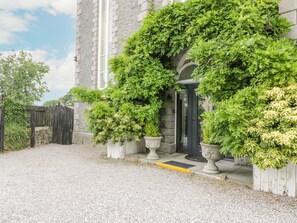 A stone building with a gravel driveway and a wooden fence. - Capel Mawr (Caernarfon)