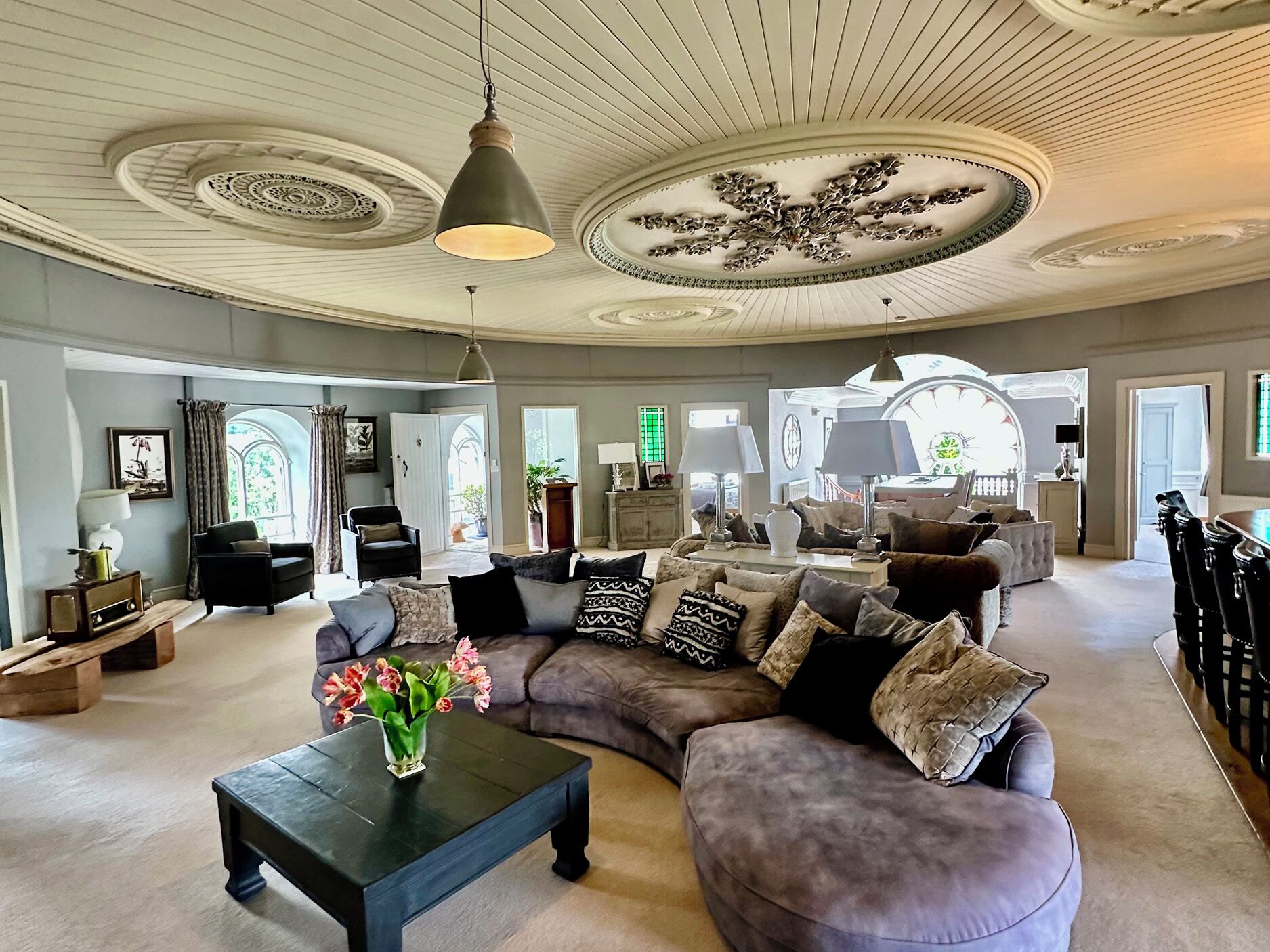 Un salon spacieux avec un grand canapé d’angle, une table basse et un lustre.