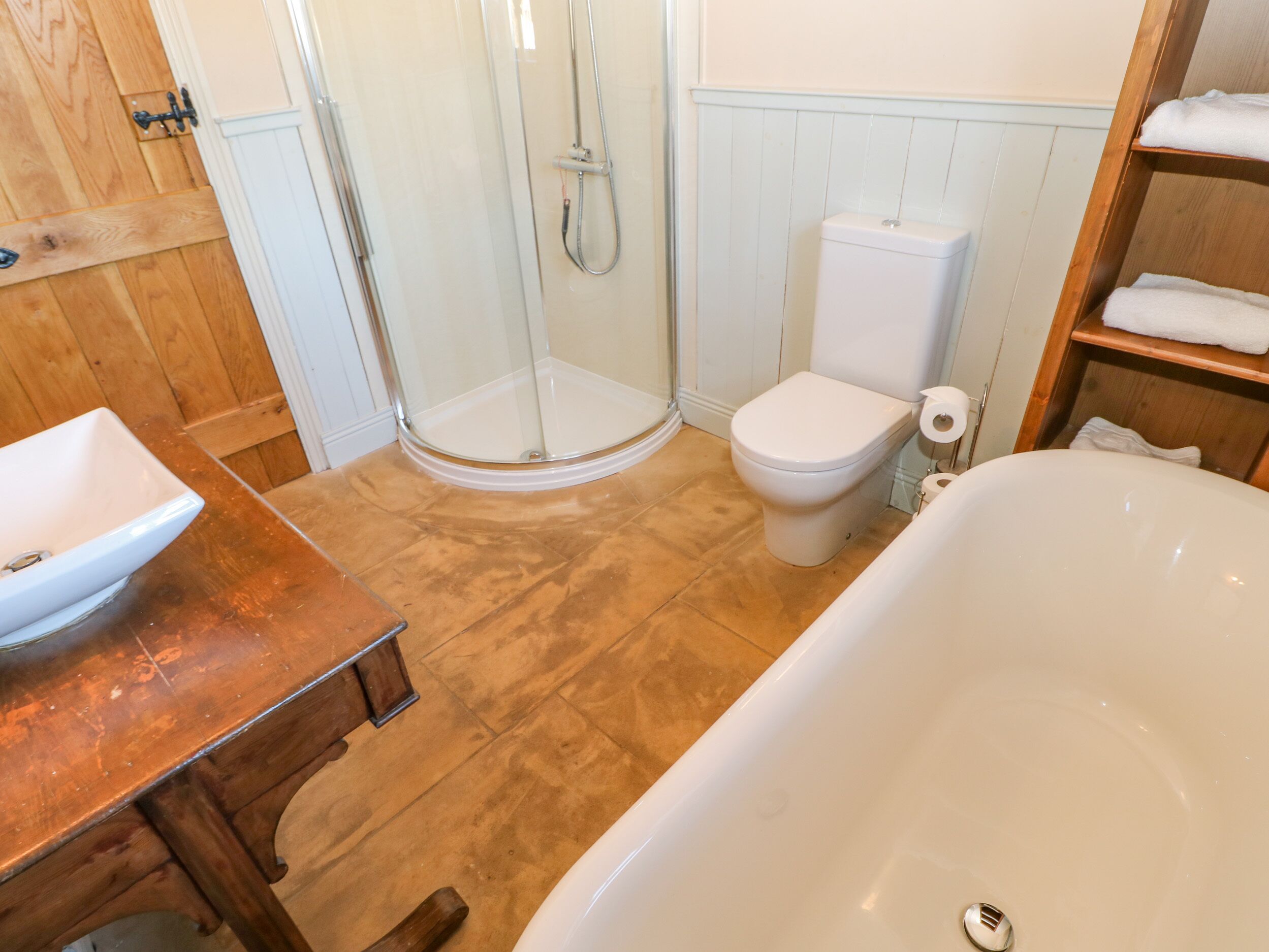 A bathroom with a wooden vanity, a glass shower enclosure, a toilet, and a bathtub.