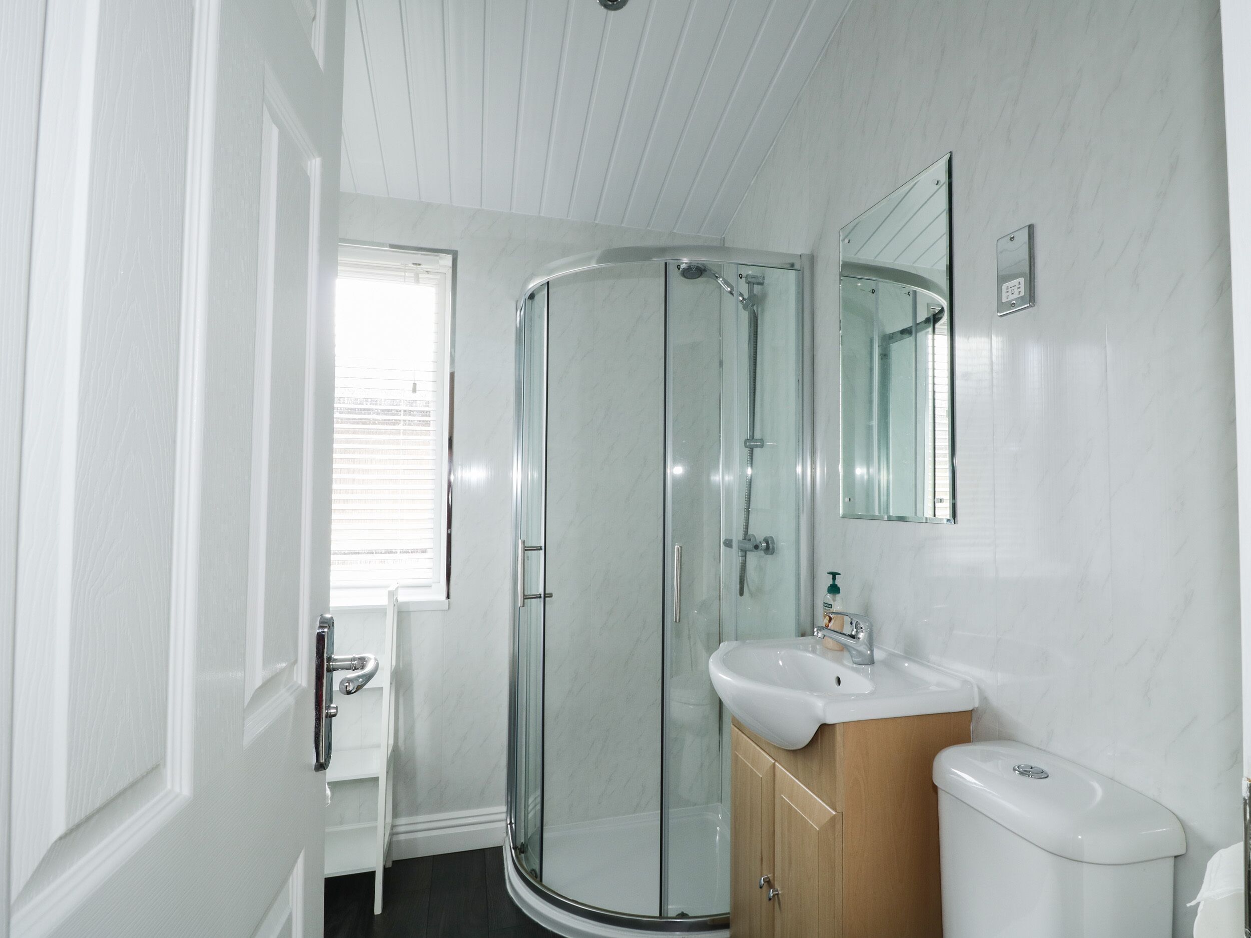 Un bagno con cabina doccia in vetro, lavandino e water.