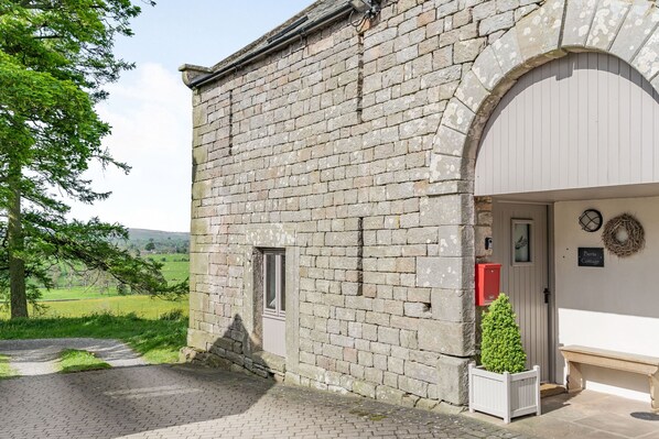 Un bâtiment en pierre doté d’une grande entrée en arc de cercle, d’une petite fenêtre et d’un banc à l’extérieur.
