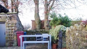 Un muro de piedra, un banco de madera y plantas en macetas en un jardín.