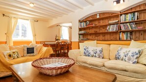 Ein gemütliches Wohnzimmer mit einer Couch, einem Couchtisch und einer B ücherwand voller Bücher.