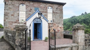 Un edificio de piedra con puerta azul y un pequeño porche.