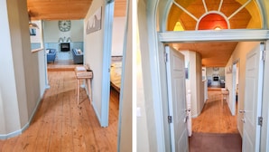 Un pasillo con suelo de madera que conduce a un dormitorio con cama y escritorio.