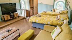 Una habitación de hotel con una cama grande, un sofá, un televisor y un armario de madera.
