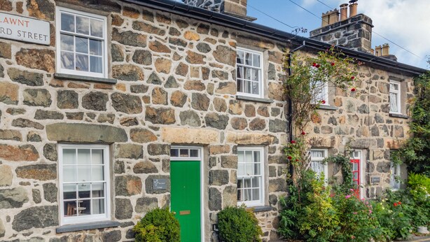 Um edifício de pedra com porta verde, janelas e uma placa com a inscrição 