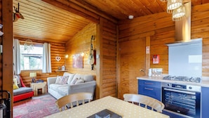 A cozy cabin interior with a dining area, kitchen, and seating space. - Harbottle Lodge (Morpeth)
