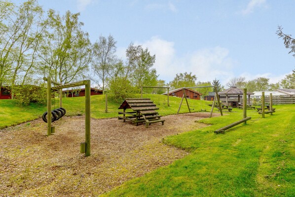 A playground with swings, a slide, and a picnic area. - Harbottle Lodge (Morpeth)