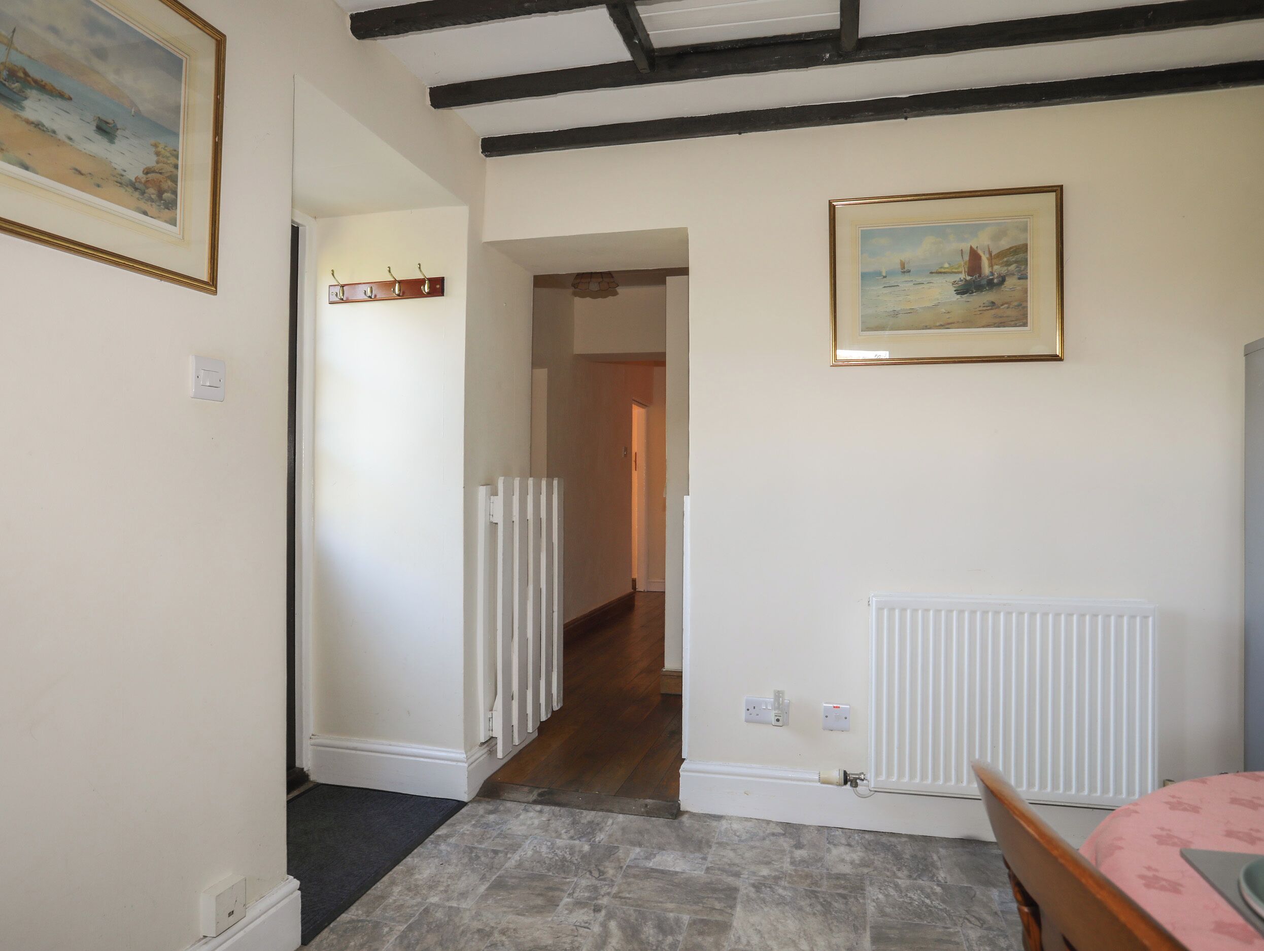 A hallway with a white radiator, a door leading to another room, and a painting on the wall.
