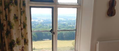 A room with a large window offering a view of a green landscape.