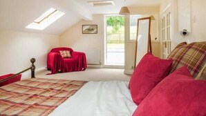 Un dormitorio con una cama, una silla roja, un espejo y una ventana.