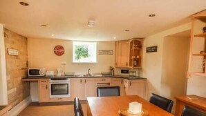 Una cocina moderna con armarios de madera, una mesa de comedor con sillas, un microondas y un ventanal que proporciona luz natural.