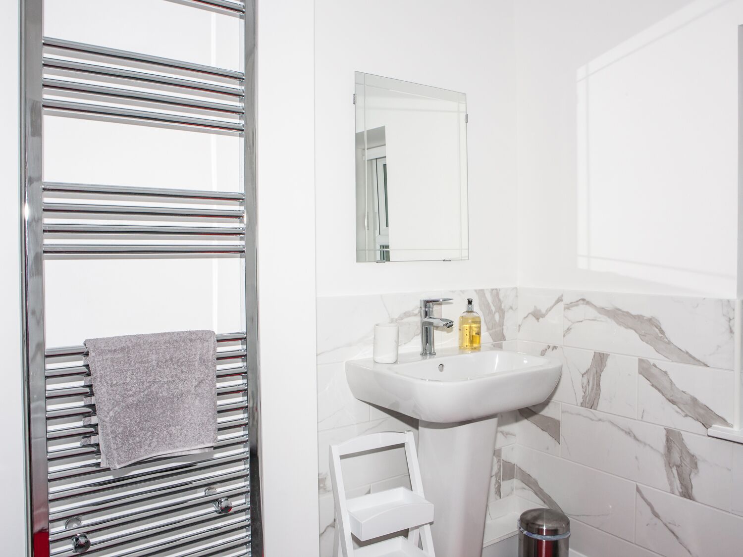 A bathroom with a white sink, a mirror, and a towel rack.
