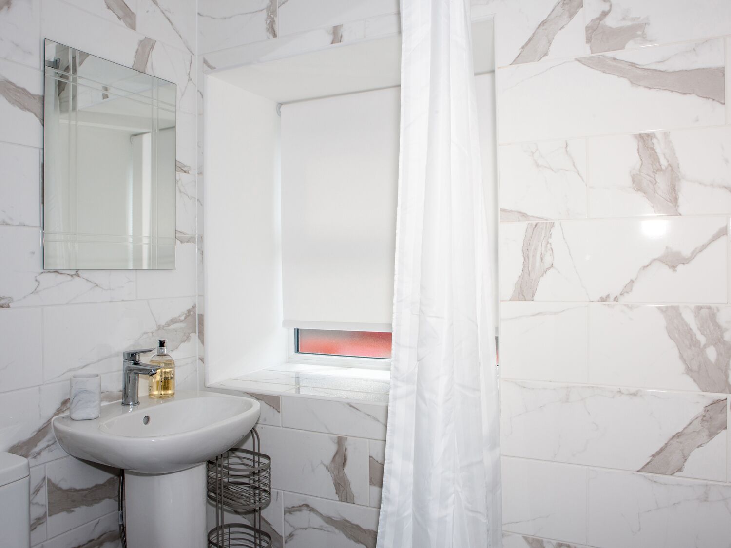 Ein Badezimmer mit einem weißen Waschbecken, einem Spiegel und einem Fenster mit Blick.