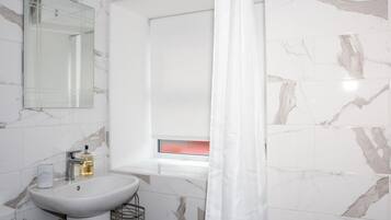Un baño con lavamanos blanco, espejo y ventana con vistas.