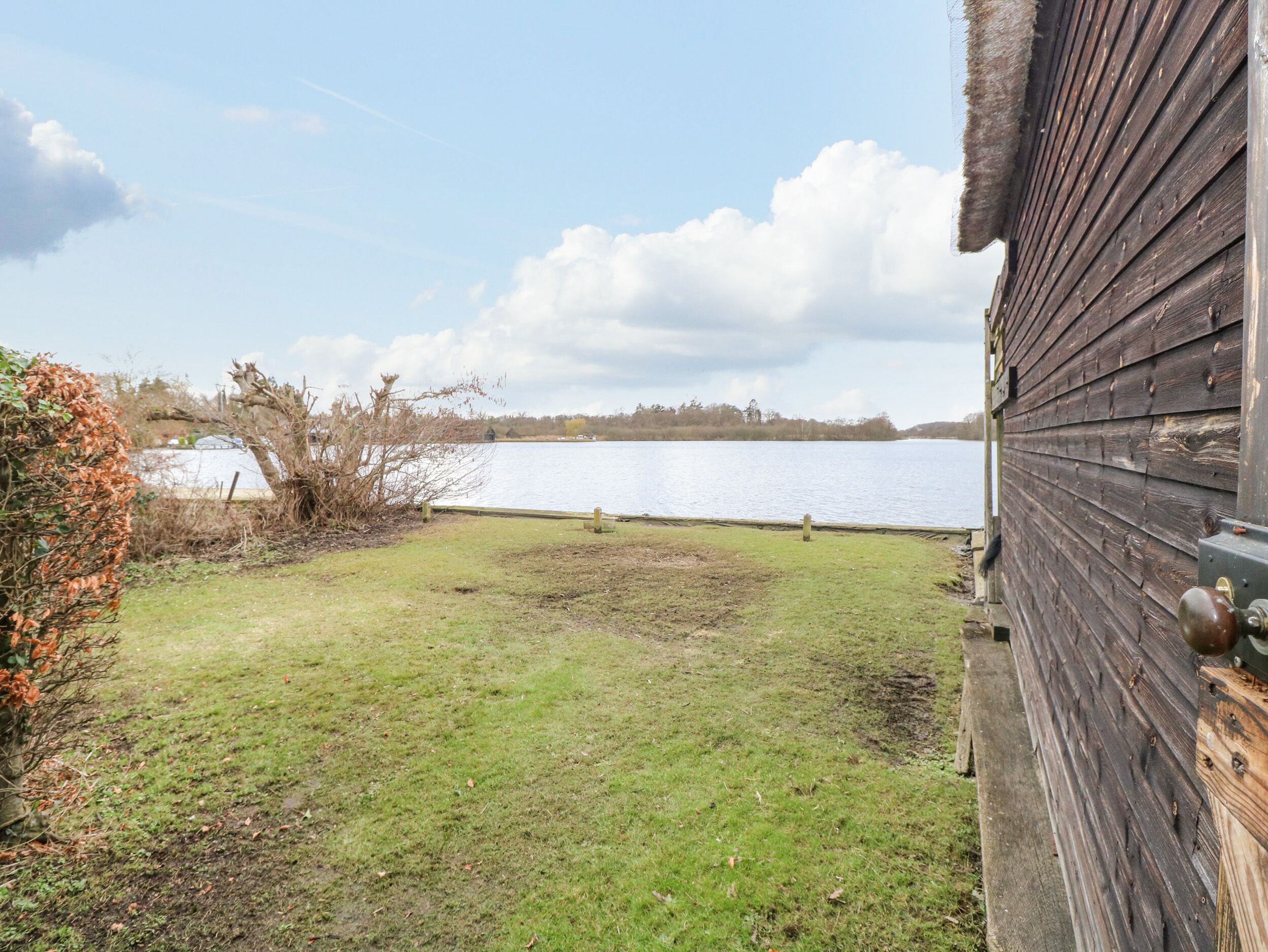A wooden building with a grassy yard and a lake in the background.