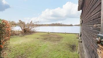 A wooden building with a grassy yard and a lake in the background.