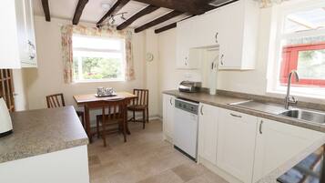 A kitchen with a wooden table, chairs, a dishwasher, and a sink.
