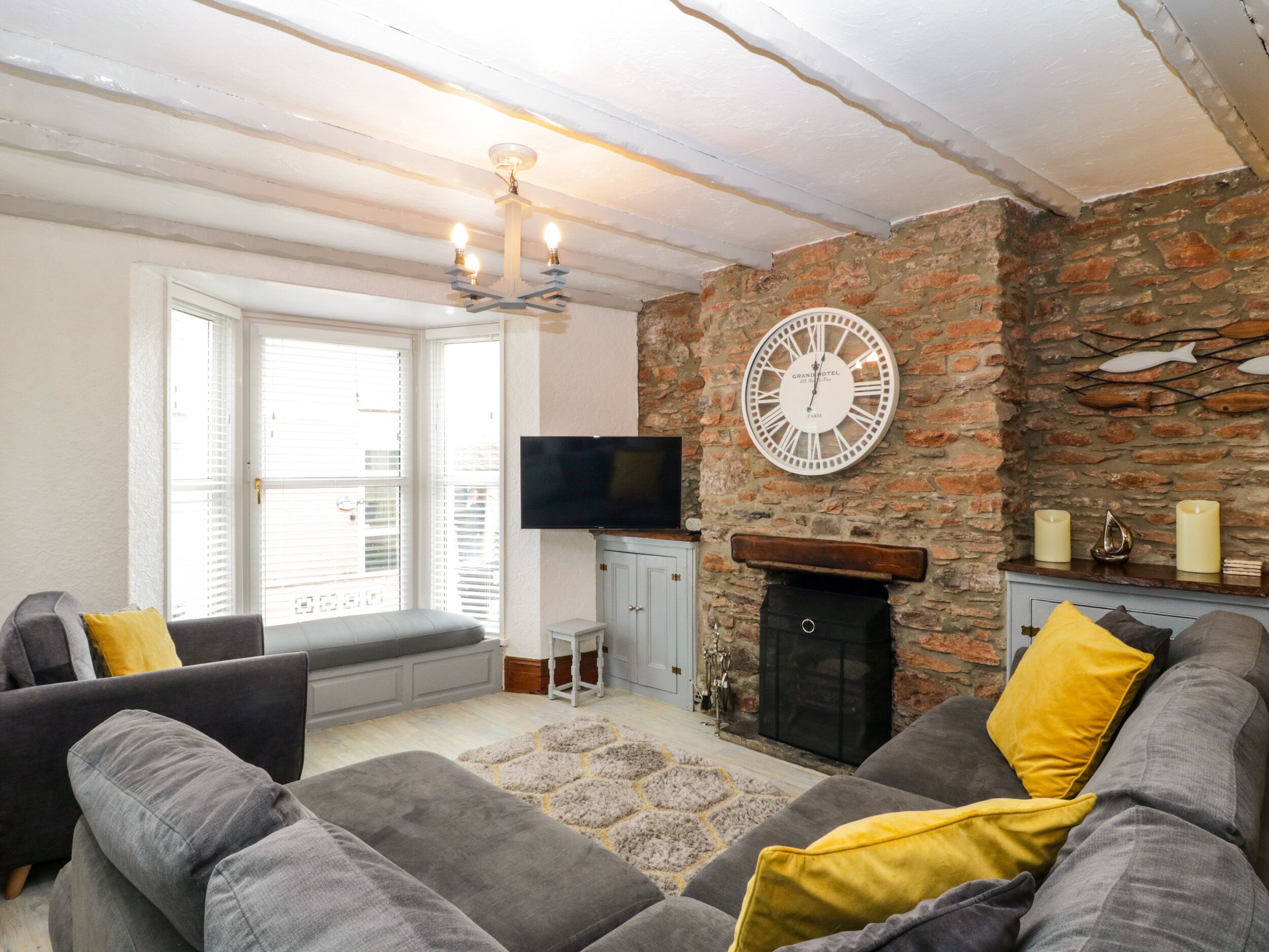 A living room with a stone wall, a fireplace, a large clock, and a television.