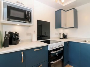 A modern kitchen with a microwave, stove, oven, and a kettle on the countertop.