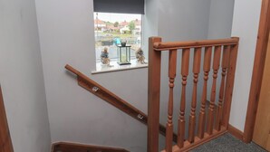 Una escalera con balaustres de madera y un ventanal con vistas al exterior.