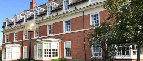A traditional brick building with multiple windows and a prominent bay window.