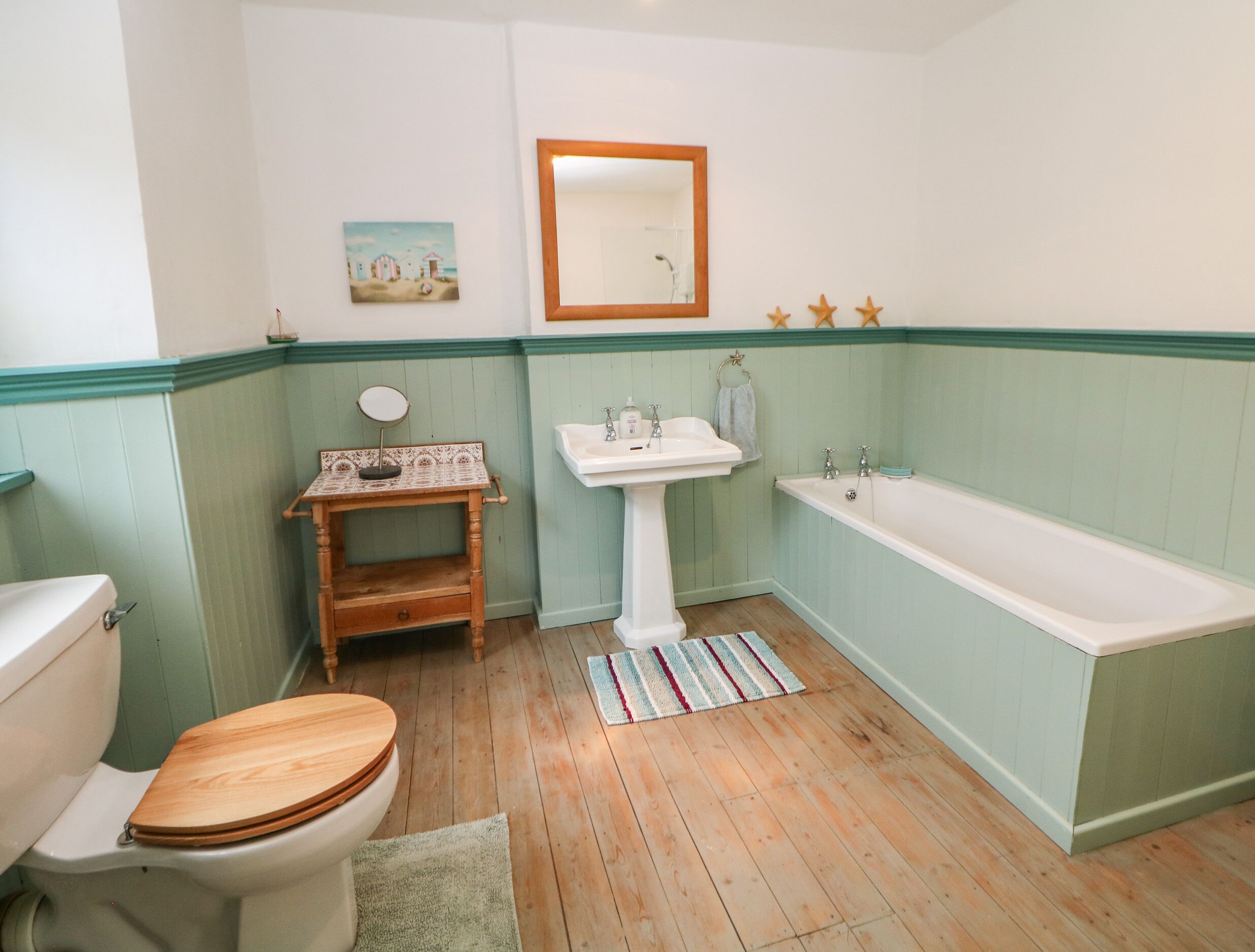 A bathroom with a wooden toilet, a pedestal sink, and a bathtub.