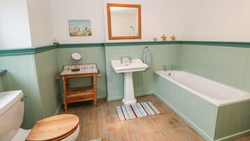 A bathroom with a wooden toilet, a pedestal sink, and a bathtub.