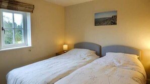 A double bed with floral bedding, a bedside lamp, and a window with curtains. - Jay's Nest (Hope Valley)