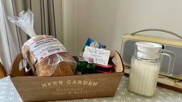 Una caja de madera con la etiqueta 'HERB GARDEN', un pan, una tarjeta y botellas sobre una mesa.