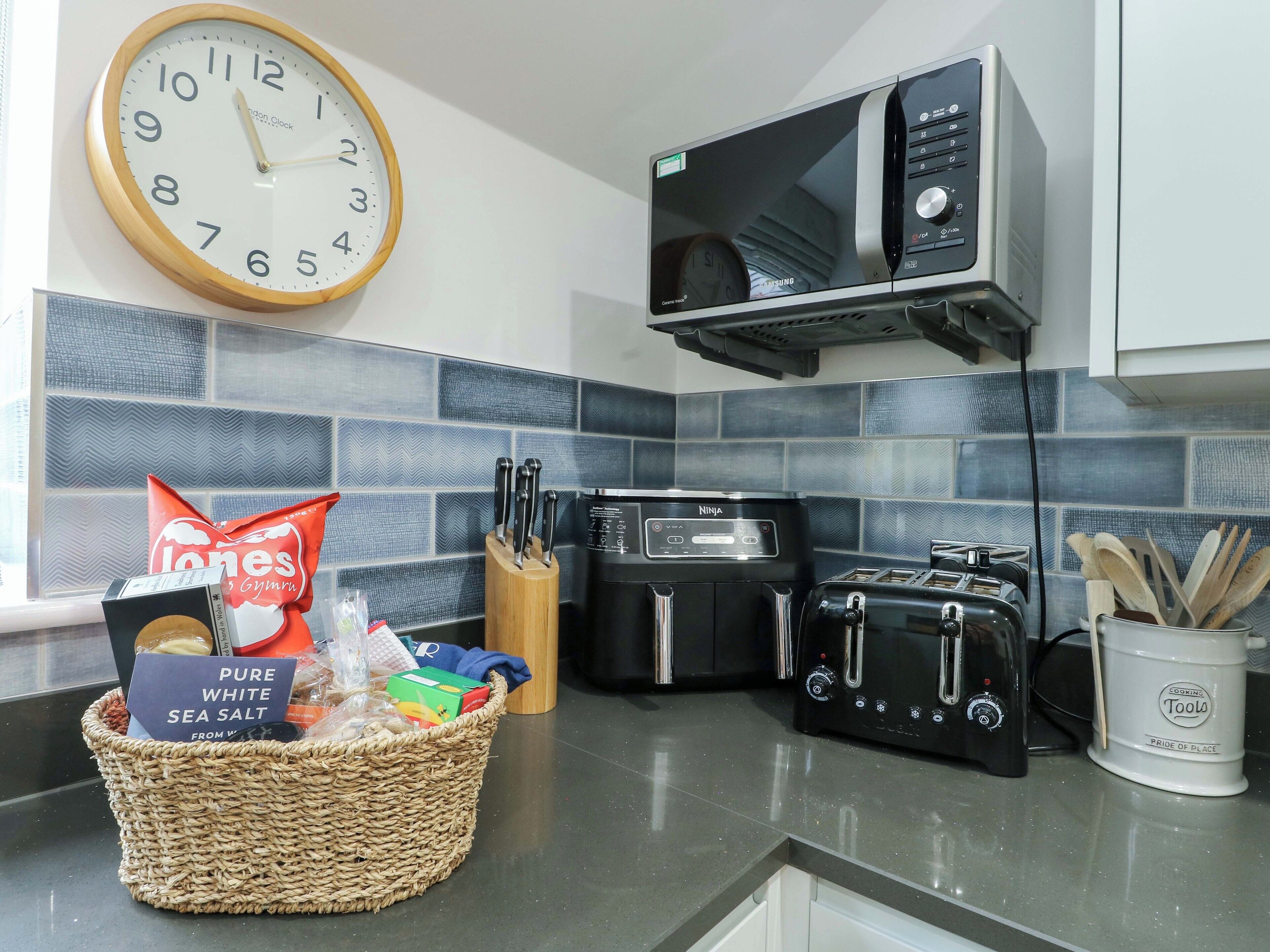 A kitchen with a microwave, toaster, and a clock on the wall.