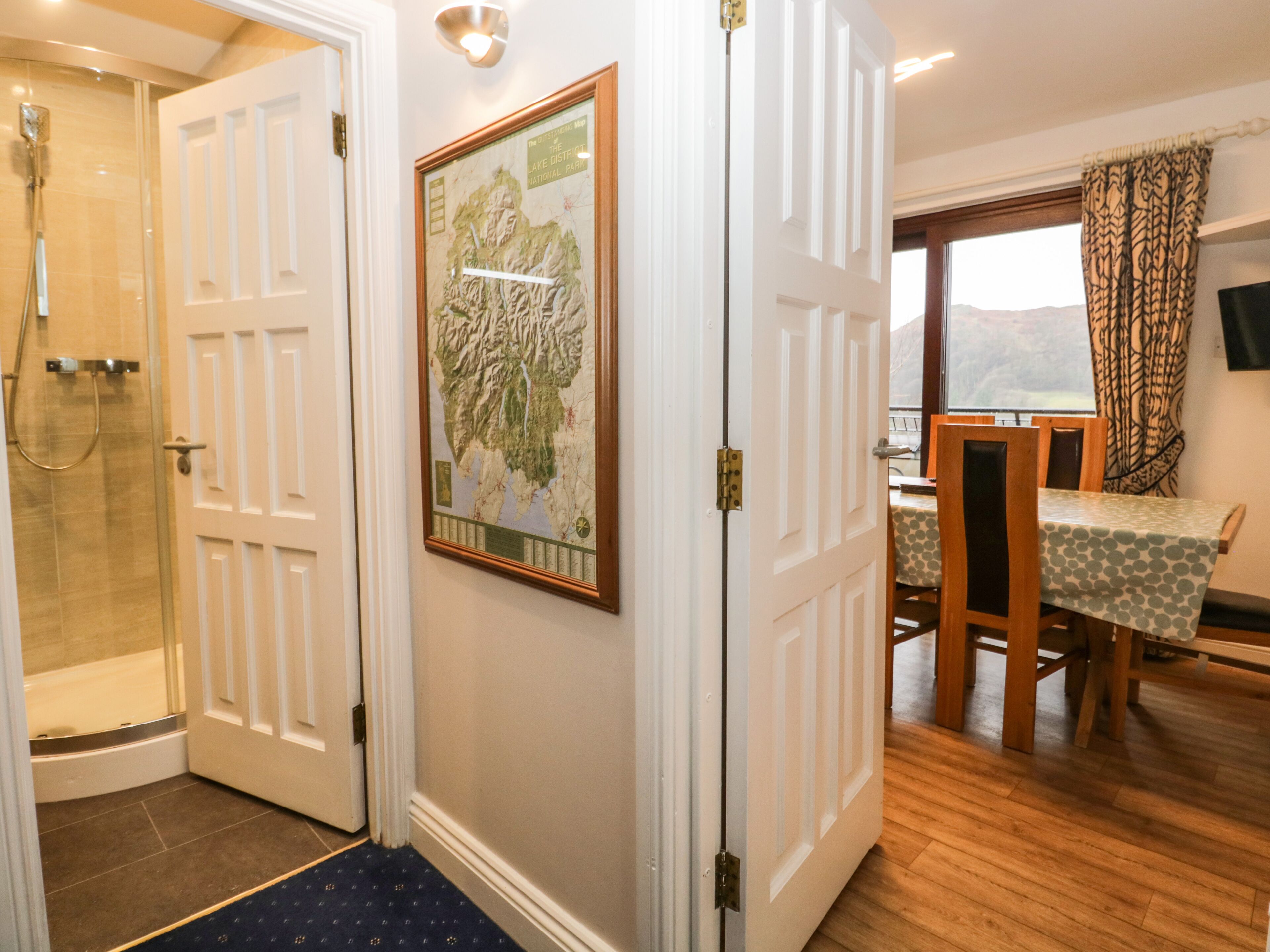 A hotel room with a shower, a dining area with a table and chairs, and a large framed map on the wall.