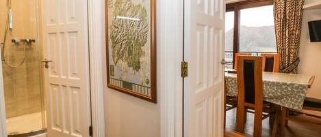 A hotel room with a shower, a dining area with a table and chairs, and a large framed map on the wall.