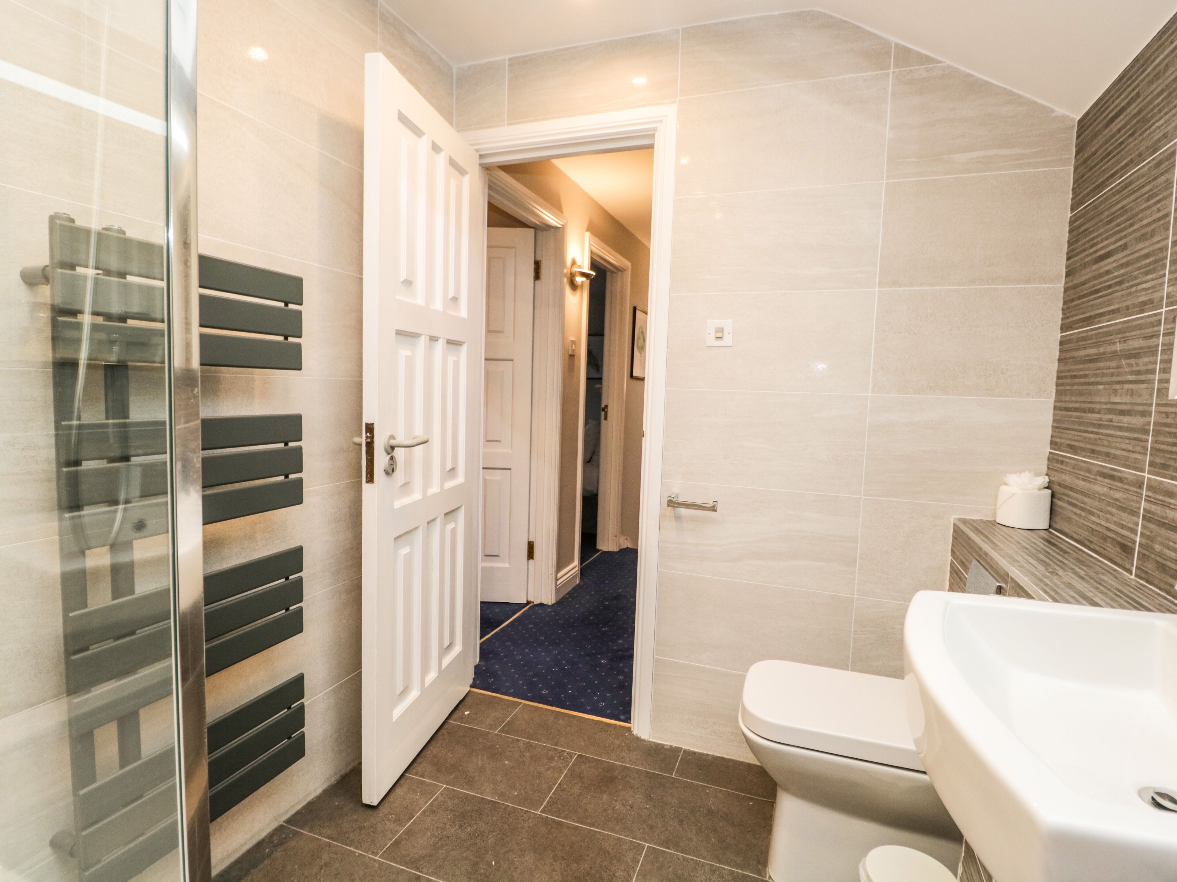 A modern bathroom with a toilet, a glass shower enclosure, and a sink.