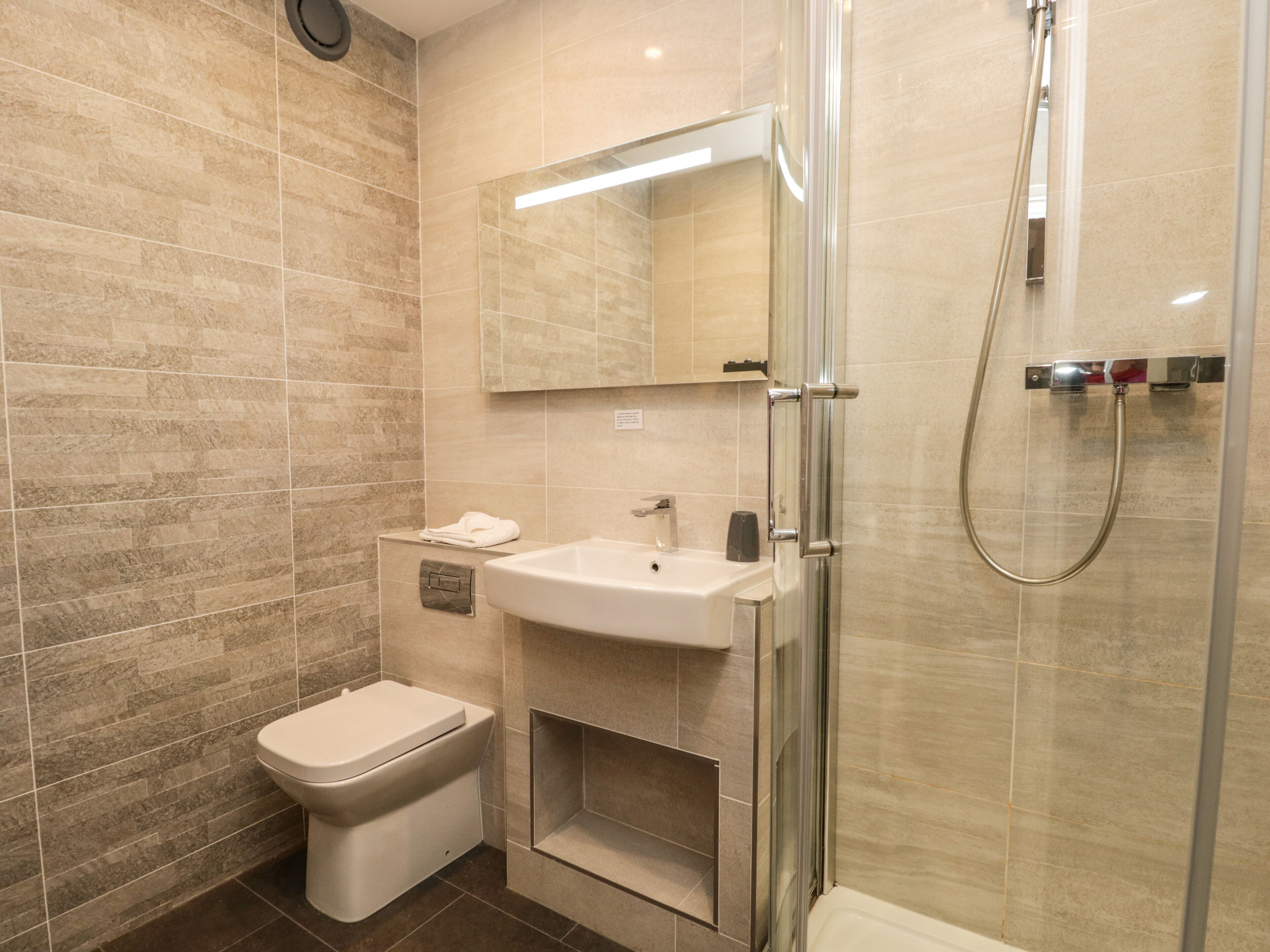 A modern bathroom with a toilet, sink, and shower.