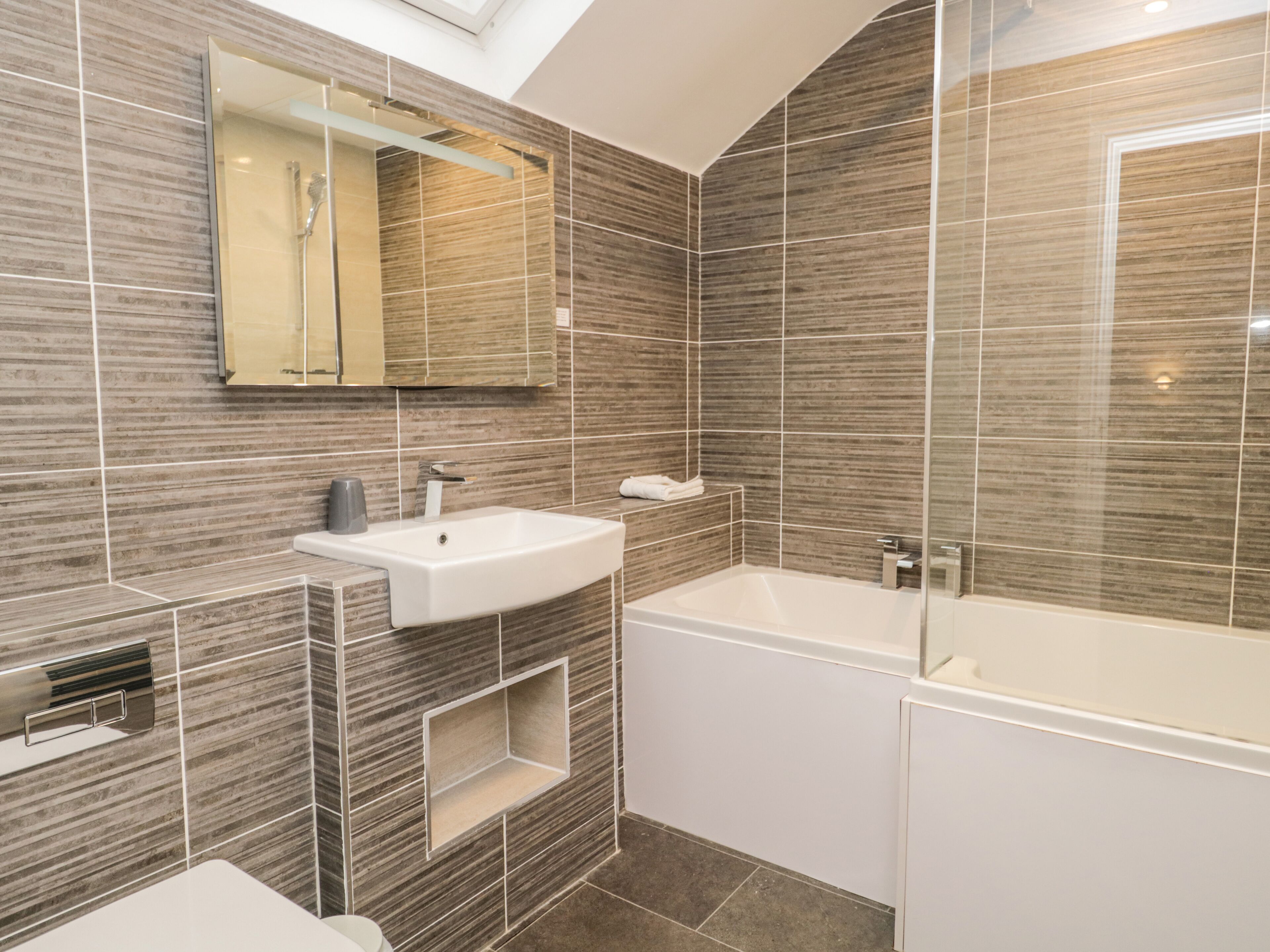 A modern bathroom with a built-in sink, a mirror, a shower, and a bathtub.