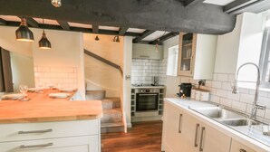 A modern kitchen with white cabinets, a wooden countertop, and a built-in oven. - 4 Masons Court (Stratford-upon-Avon)