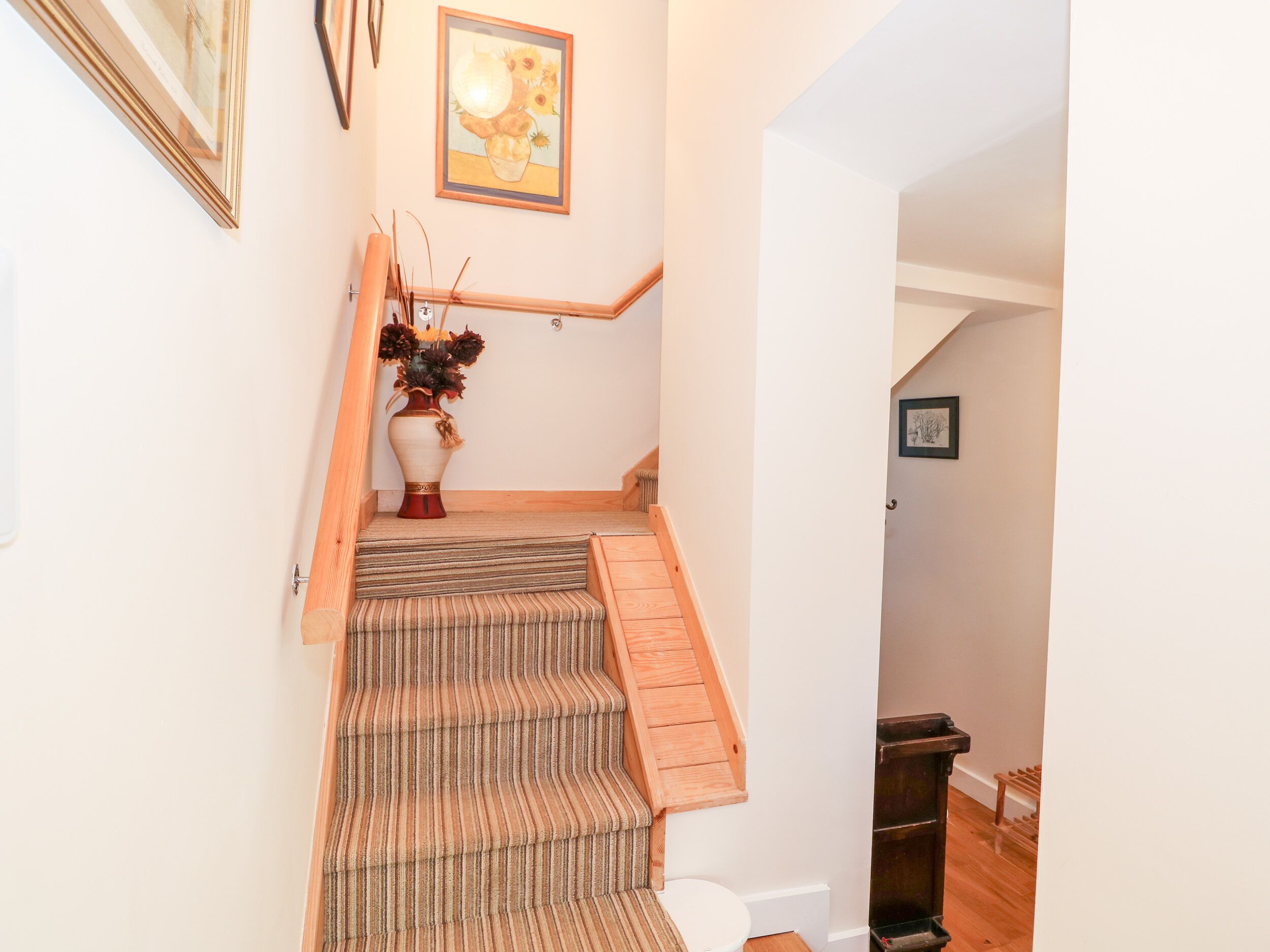 Un escalier avec des marches en bois et une moquette à rayures.