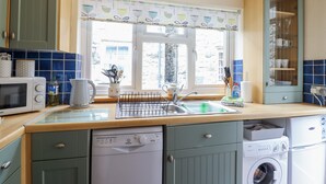 A kitchen with a microwave, sink, and washing machine. - Cae Tanws Bach (Dolgellau)