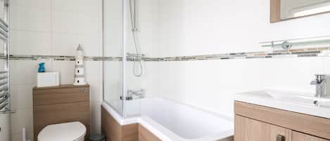 Un baño moderno con ducha de vidrio, bañera blanca y muebles de madera.